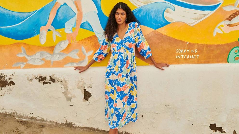 Woman in colourful summer dress leaning on wall